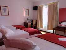 Residencial Alcides auf Sao Miguel, gemütliches Zimmer mit drei Einzelbetten und warmem Ambiente, ideal für erholsame Nächte.