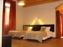 Apartaments Kosmos auf der Insel Faial, gemütliches Zimmer mit zwei Einzelbetten, warmen Holzakzenten und orangen Vorhängen.