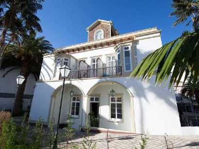 Stilvolles Herrenhaus Casa das Palmeiras auf den Azoren, mit Balkon, Palmen im Vorgarten und klassizistischer Fassade