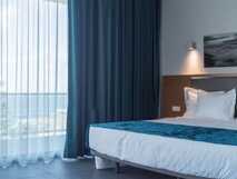 Whales Bay Hotel Apartamentos auf Sao Miguel, modernes Zimmer mit großem Bett und Meerblick, ideal für erholsamen Urlaub.