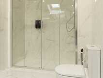 Aparthotel Horta Bay – moderne, helle Badezimmer-Oase mit großzügiger Regendusche und edlem Marmor-Design.