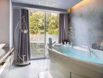 Octant Hotel Furnas, Sao Miguel – luxuriöses Badezimmer mit moderner Badewanne und entspanntem Ausblick auf grüne Natur in exklusivem Ambiente.