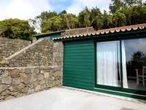 Traditionelles Ferienhaus O Farrobo mit grüner Fassade, Natursteinmauer und Blick ins Grüne auf São Jorge, Azoren