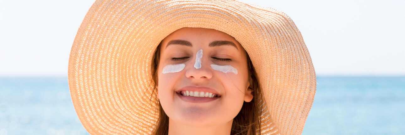 Eine lächelnde Frau mit Sonnenhut steht entspannt am Strand der Kapverden.