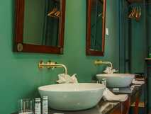 Elegantes Bad mit zwei Waschbecken, goldenen Wasserhähnen und antiken Spiegeln im Solar do Cantos Botanic House.