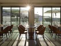 Rooftop-Bar mit weißen Stühlen und Sonnenschirmen am Abend