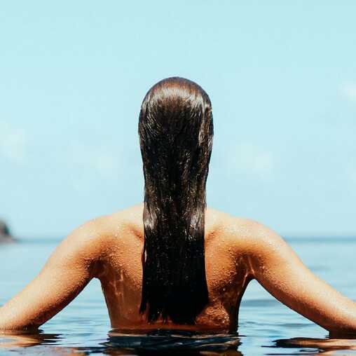 Frau genießt die Ruhe eines Naturpools auf Madeira, umgeben von Felsen und Meer