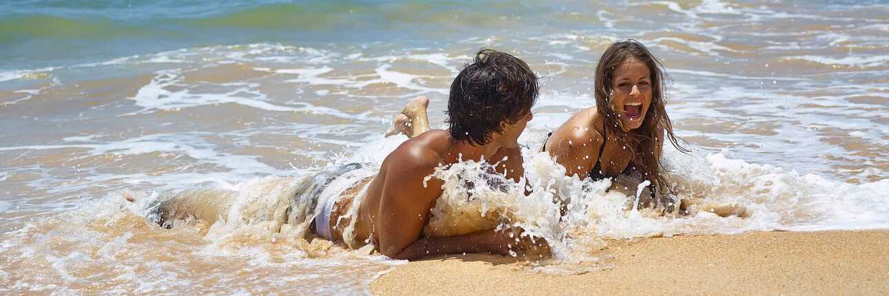 Ein junges Paar liegt am Strand in der Brandung des Meeres