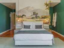 Gemütliche Junior Suite mit Doppelbett und kunstvoller Wandmalerei im Botanic House Solar do Cantos.
