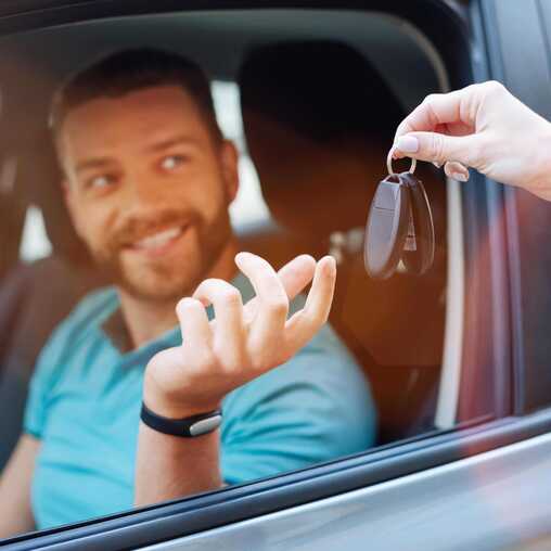 Mann nimmt Autoschlüssel seines mietwagens entgegen