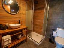 The Plantation Faial – Modernes Badezimmer mit stilvoller Holzoptik und komfortabler Ausstattung für erholsame Urlaubstage.