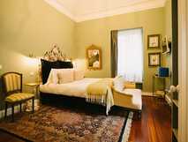 Gemütliches Doppelzimmer mit antikem Bettkopfteil, Teppich, stilvollen Möbeln und Dekorationen