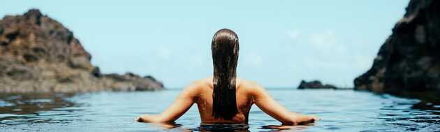 Frau genießt die Ruhe eines Naturpools auf Madeira, umgeben von Felsen und Meer