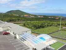 Pension Al-Nova Vista auf Pico - modernes Hotel mit Poolbereich und malerischem Blick auf die grüne Landschaft und das Meer.