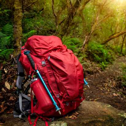Ein Tagesrucksack mit Regenhülle, Stöcken und einer Wasserflasche sind essentiell zum Wandern