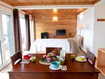 Gemütliches Ferienzimmer mit Frühstückstisch, Panoramafenstern und Holzdesign – perfekt für erholsame Urlaubstage mit picotours.