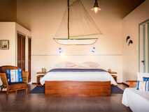 Großes Doppelzimmer mit großem Doppelbett und Stuhl im Guesthouse O'Zimbreiro