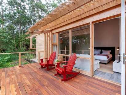Holzbungalow der Cabanas da Viscondessa mit zwei roten Stühlen auf privater Terrasse im Grünen auf São Jorge