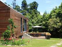 Modernes Holzhaus der Quinta da Mó inmitten eines grünen Gartens mit Blumen, Wiese und Bäumen auf São Miguel