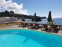Poolbereich des Vinha D’Areia Beach Hotels mit Liegen und Meerblick auf São Miguel, Azoren.