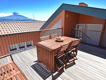 Casa da Baia auf Faial – Sonnige Dachterrasse mit Holzmöbeln und Blick auf einen Berg unter klarem blauem Himmel.