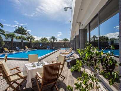 Poolterrasse der Antillia Hotel Apartments mit gedecktem Frühstückstisch, Liegestühlen und Palmen in Ponta Delgada