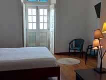 Hotel Savana Fogo, einfaches, helles Zimmer mit großem Bett.