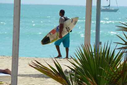 Surfer trägt sein Board am Strand von Boa Vista, Kapverden – bereit für die nächste Welle.