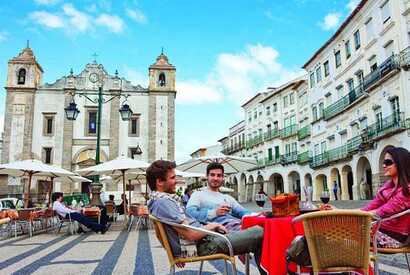 Menschen sitzen in einem Café in der Altstadt von Evora, einer Stadt, die zu den Sehenswürdigkeiten Portugals gehört.