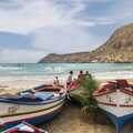 Bunte Fischerboote am Strand von Tarrafal auf Santiago, Kapverden – mit Blick auf die malerische Bucht und Berge im Hintergrund.