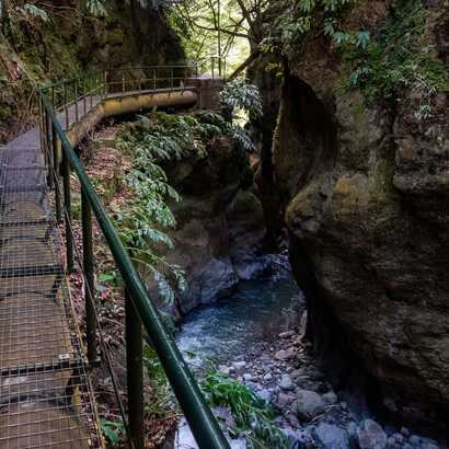 Malerischer Wanderpfad durch grüne Schlucht mit klarer Bergquelle, ideal für Naturerlebnisse.
