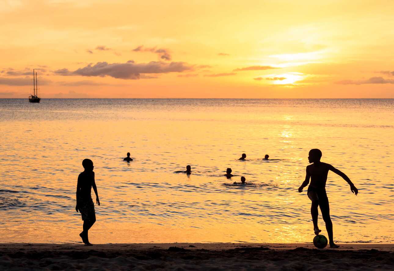 Kinder spielen Fußball auf Kap Verde am Strand im Sonnenuntergang