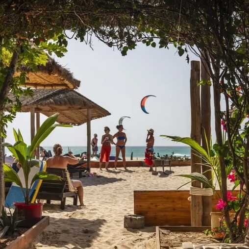 Strandbar mit Palmenblick auf das Meer und Kitesurfer am Horizont auf den Kapverden.