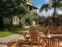 Casa Portuguesa Boutique Hotel auf Sao Miguel, sonnige Terrasse mit gemütlichen Holzmöbeln und mediterranem Flair, ideal zum Entspannen und Genießen bei picotours.