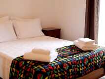Gemütliches Doppelzimmer mit bunt gemusterter Decke und frischen Handtüchern – Ihr perfekter Rückzugsort bei picotours.