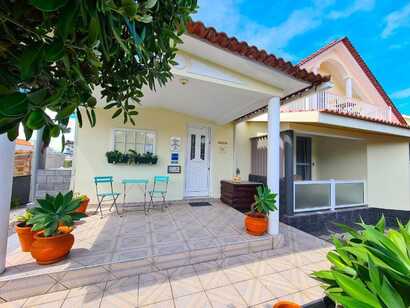Eingangsbereich des Calma do Mar Guesthouse mit heller Fassade, kleiner Sitzgruppe und Pflanzen in bunten Töpfen auf Pico