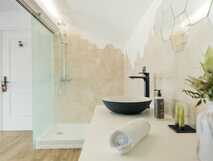 Stylisches Badezimmer mit Waschtisch, Rundspiegel und hexagonalen Natursteinfliesen.