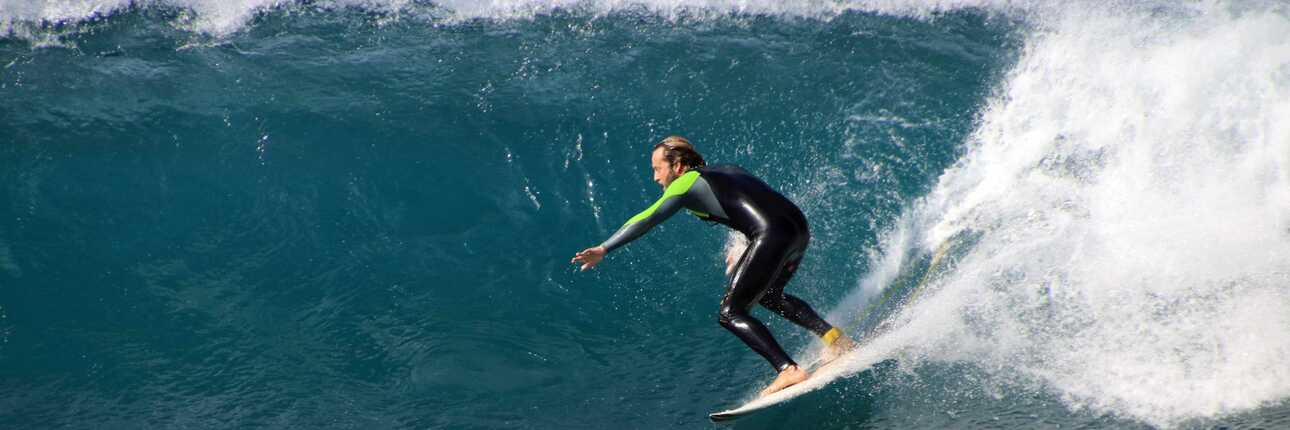Surfer reitet bei sonnigem Wetter eine große Welle vor der Küste von Boa Vista auf den Kapverden.