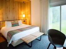 Furnas Lake Villas auf São Miguel, gemütliches Zimmer mit Holzakzenten und Blick in den grünen Garten – ideal für erholsame Aufenthalte bei picotours.