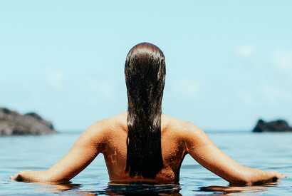 Frau genießt die Ruhe eines Naturpools auf Madeira, umgeben von Felsen und Meer