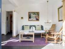 Estrela do Atlantico auf Faial, gemütliches Wohnzimmer mit Holzmöbeln, Sofa, lila Teppich und Kunst an der Wand.