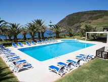 Sao Jorge Garden - Moderner Poolbereich mit Liegen, Palmen und Meerblick auf der grünen Insel Sao Jorge, ideal für Entspannung und Genuss.