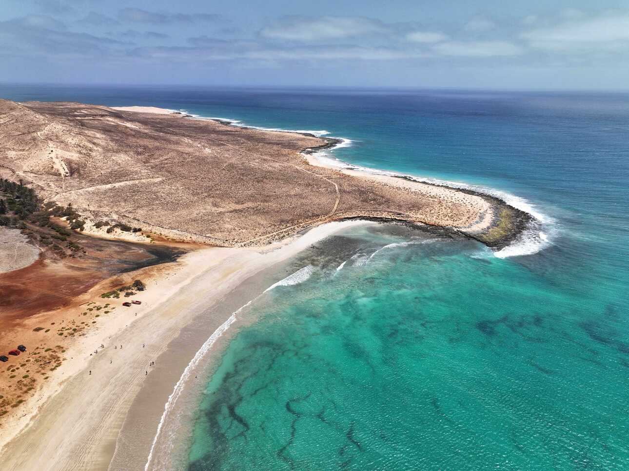 Weitläufiger Sandstrand auf den Kapverden mit türkisblauem Wasser und sanfter Küstenbucht.