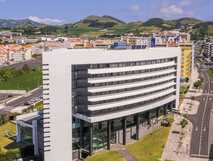 Moderne Fassade des The Lince Azores Hotels in Ponta Delgada mit Blick auf Stadt, grüne Hügel und die Hauptstraße.