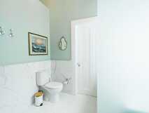 Modernes Bad mit Marmorfliesen, WC, schlichter Deko und Wandbild