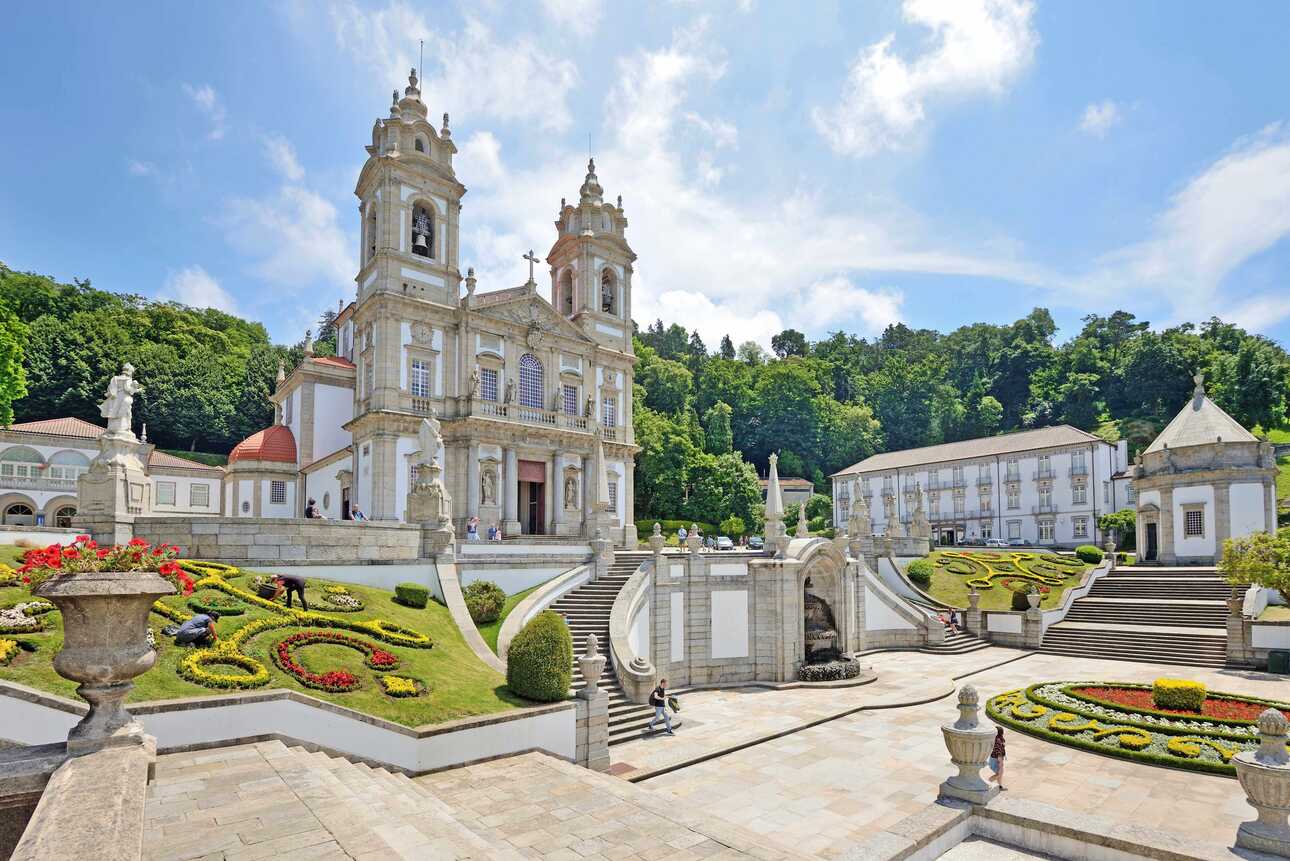 Eine wunderschöne in helltönen gehaltene Kirche mit prachtvollen Blumenbeeten davor, ein Highlight in Braga