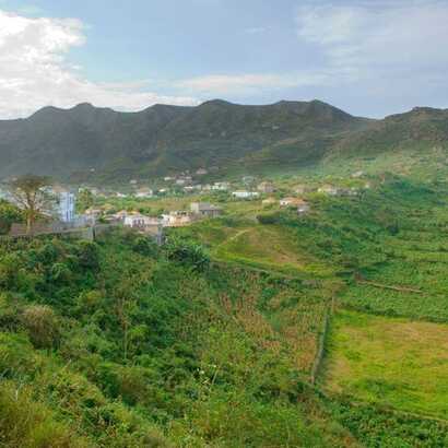 Grüne Hügellandschaft auf der Kapverden-Insel Brava mit Blick auf verstreute Häuser und bewirtschaftete Felder.