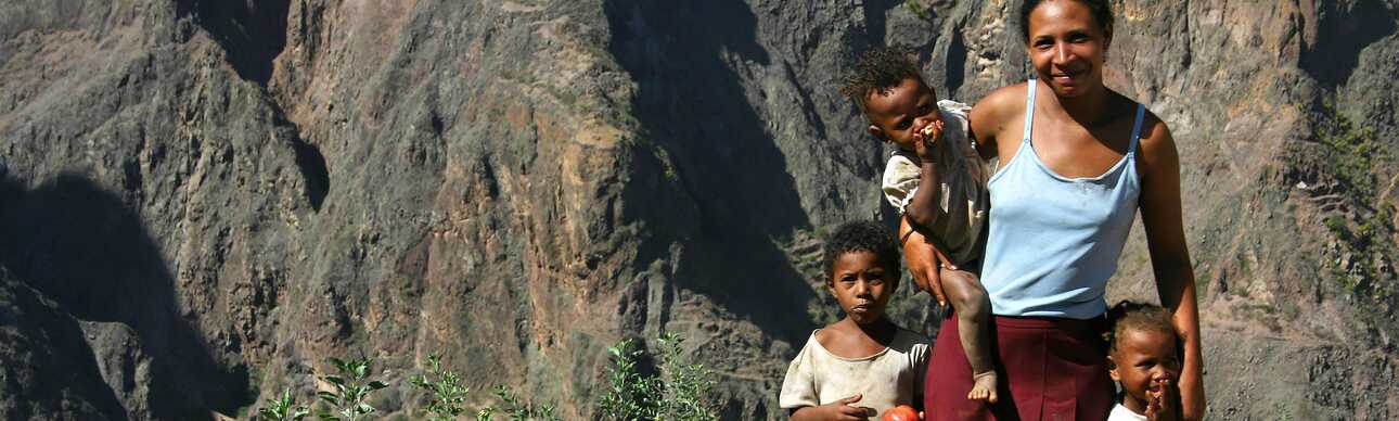 Eine Mutter wandert mit ihrem Kind durch die beeindruckende Berglandschaft der Kapverden.