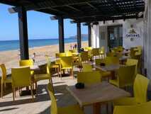 Strandcafé mit sonnengelben Stühlen und Meerblick – perfekte Entspannung mit picotours.