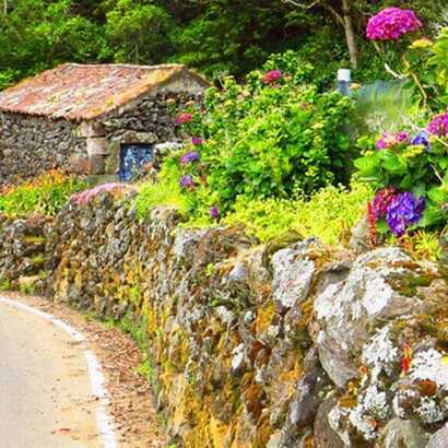Eine verwundene Straßen, eine alte Ruine und Blumen in voller Pracht auf Terceira
